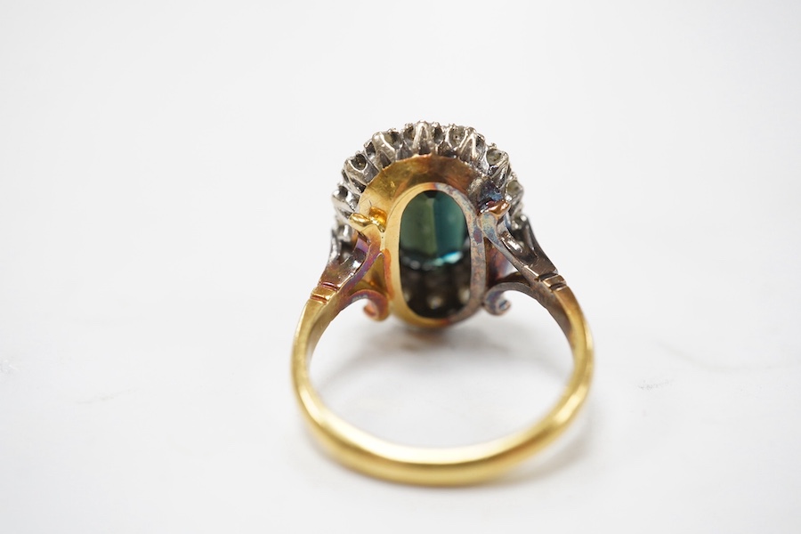 An 18ct, dark green sapphire and diamond set oval cluster ring, size N/O, gross weight 8.6 grams, the Australian sapphire weighing approximately 3.50ct, the total diamond weight approximately 0.64ct. Condition - fair